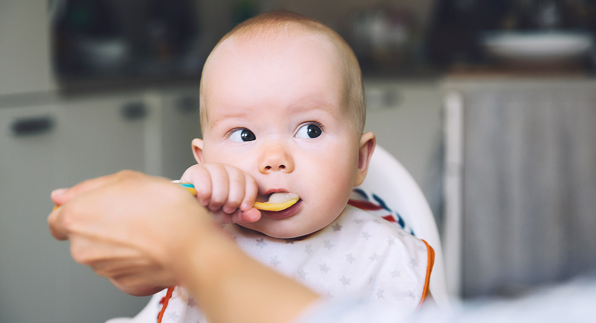 Banner baby eating holding spoon