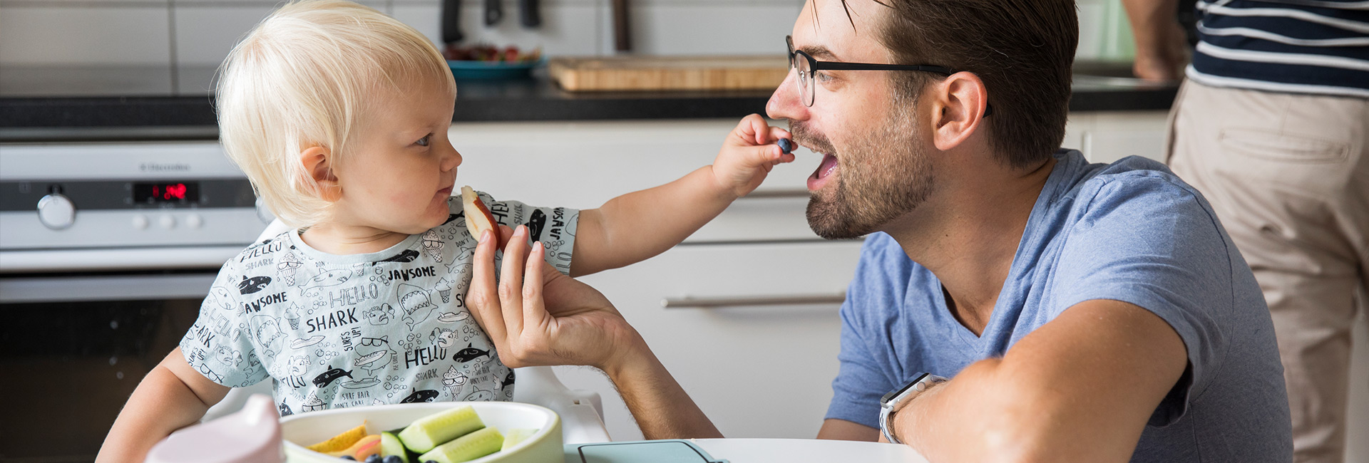 Baby feeding father a blueberry