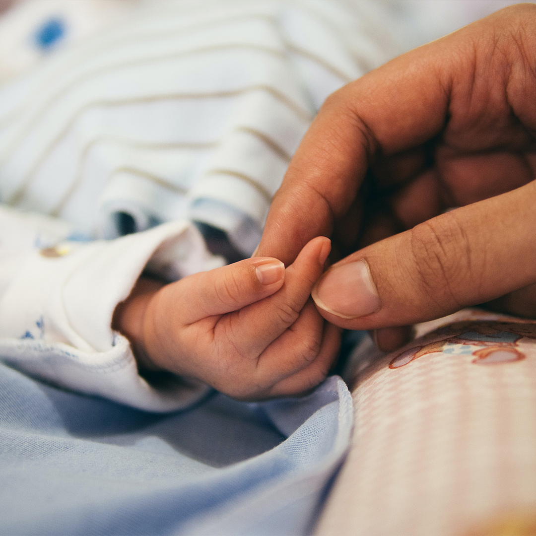 Baby and parent holding hands